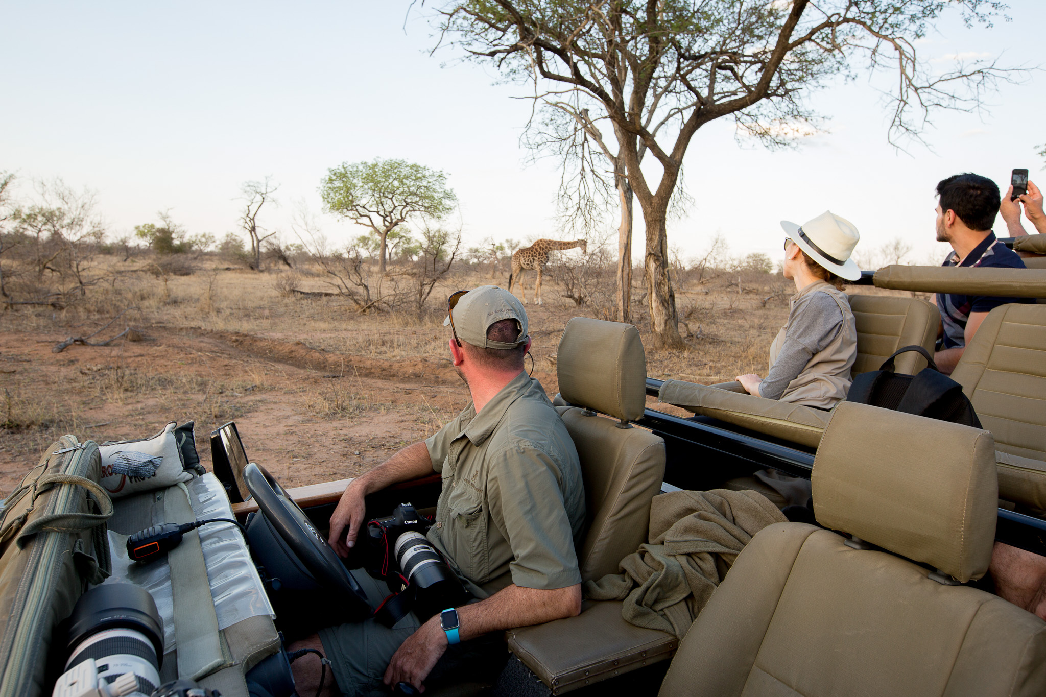 Louise Meyer Photography - man on safari vehicle looking at a giraffe