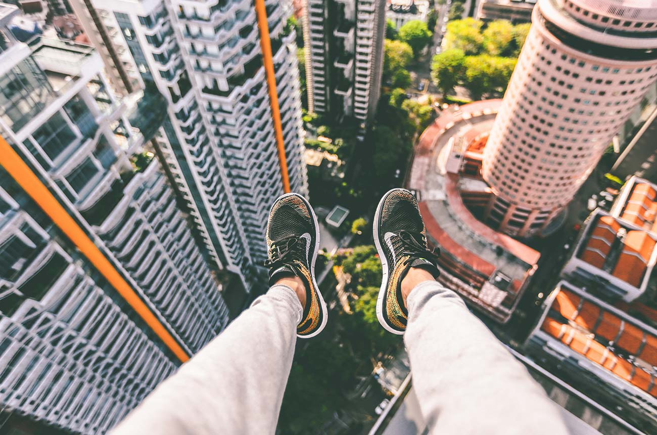 feet hanging from a high place overlooking skyscrapers