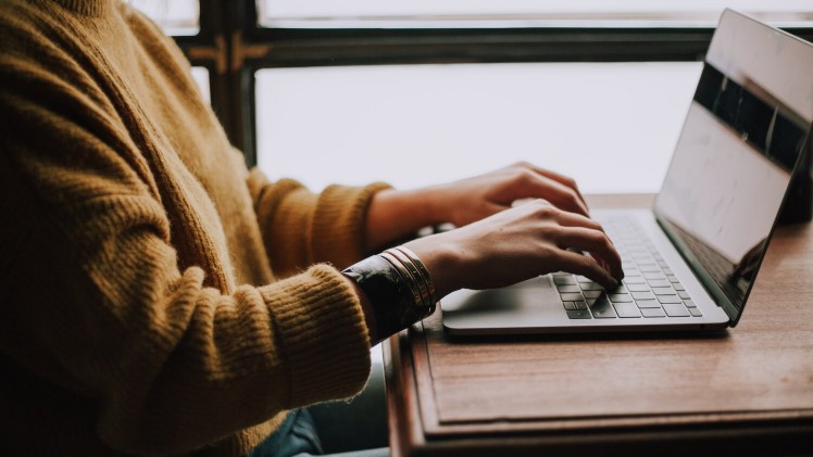 Mitarbeiterin nutzt digitale Wissensdatenbank am Laptop