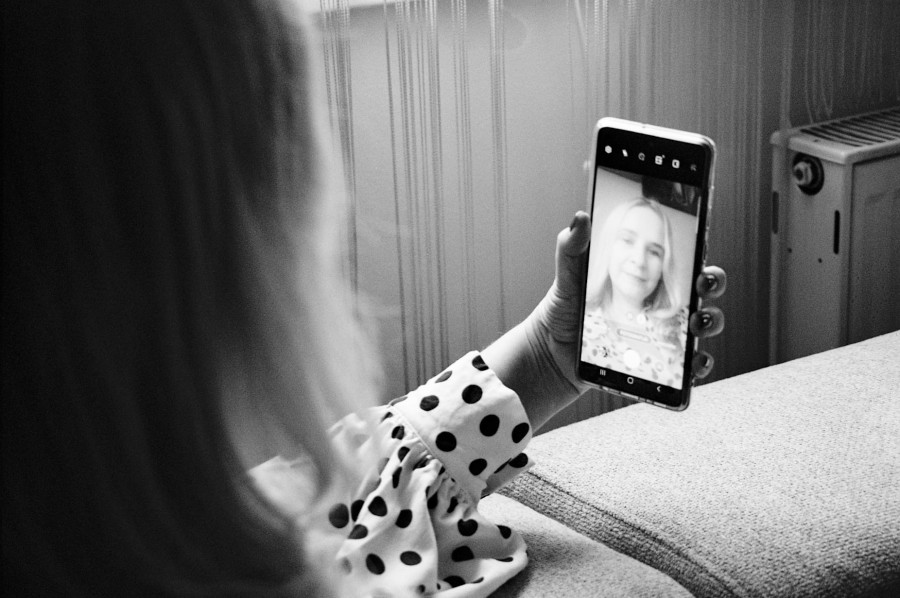 žena oboljela od raka dojke gleda u svoj odraz u mobitelu zahvalna što je nakon komplikacija doma