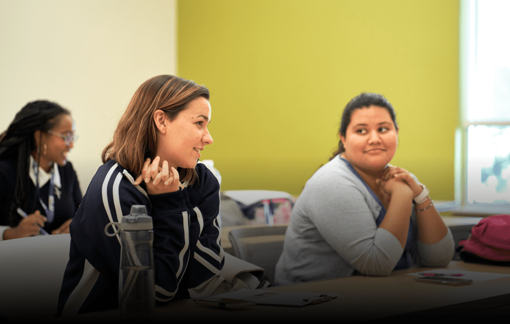 Two Relay students at a desk, smiling during a workshop.