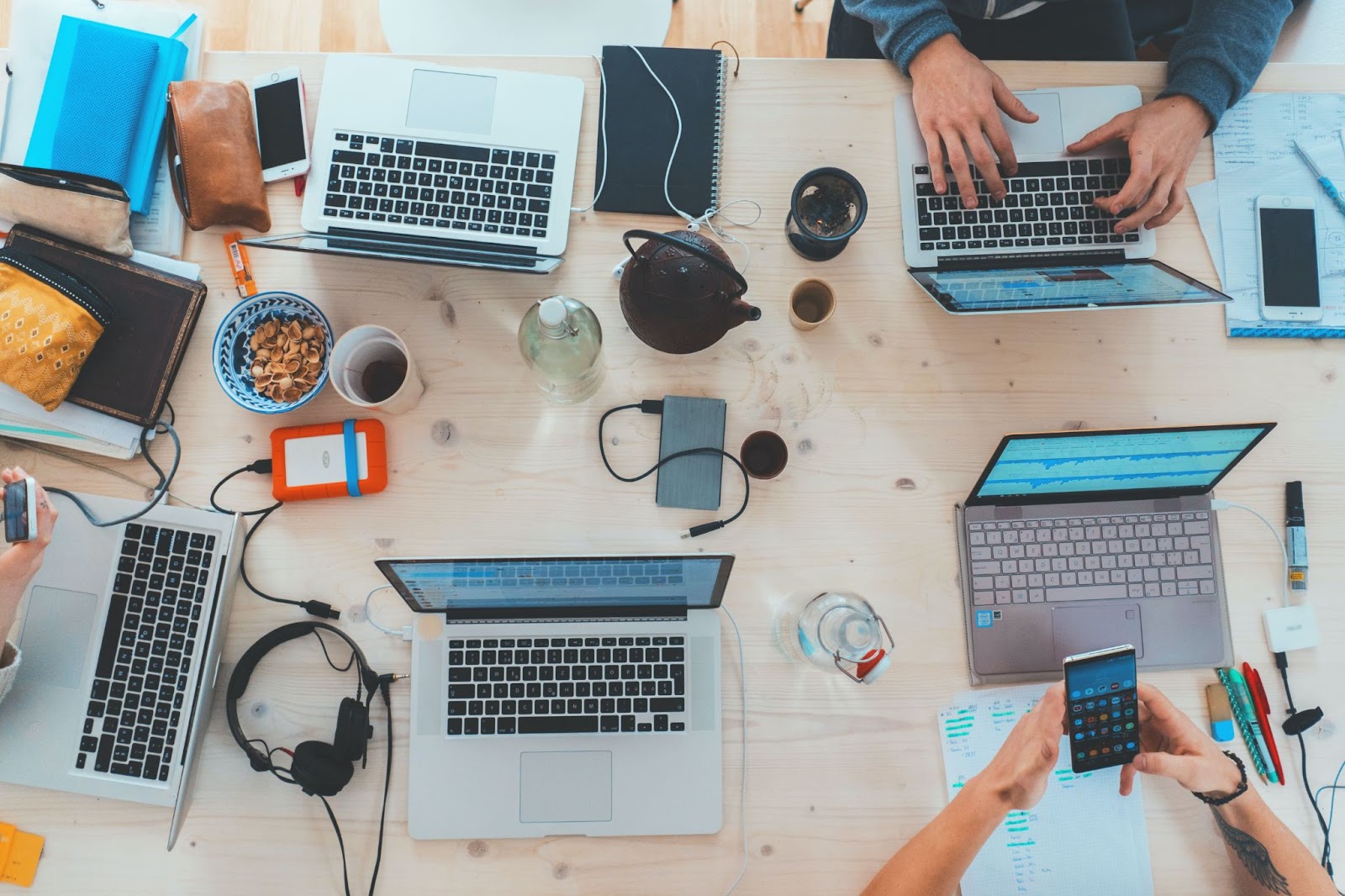 5 ordinateurs vus du dessus posés sur une table en bois