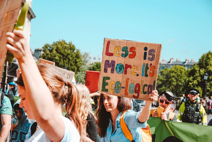Manifestation avec écrit sur un carton : "Less is more. It's eco-logical".