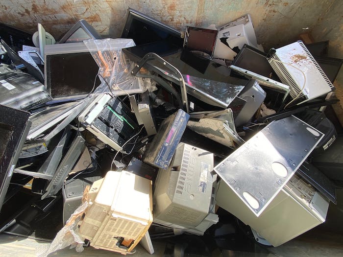 Un monticule de déchets électroniques composé de vieux ordinateurs, d'écrans d'ordinateurs et de télévision cassés.