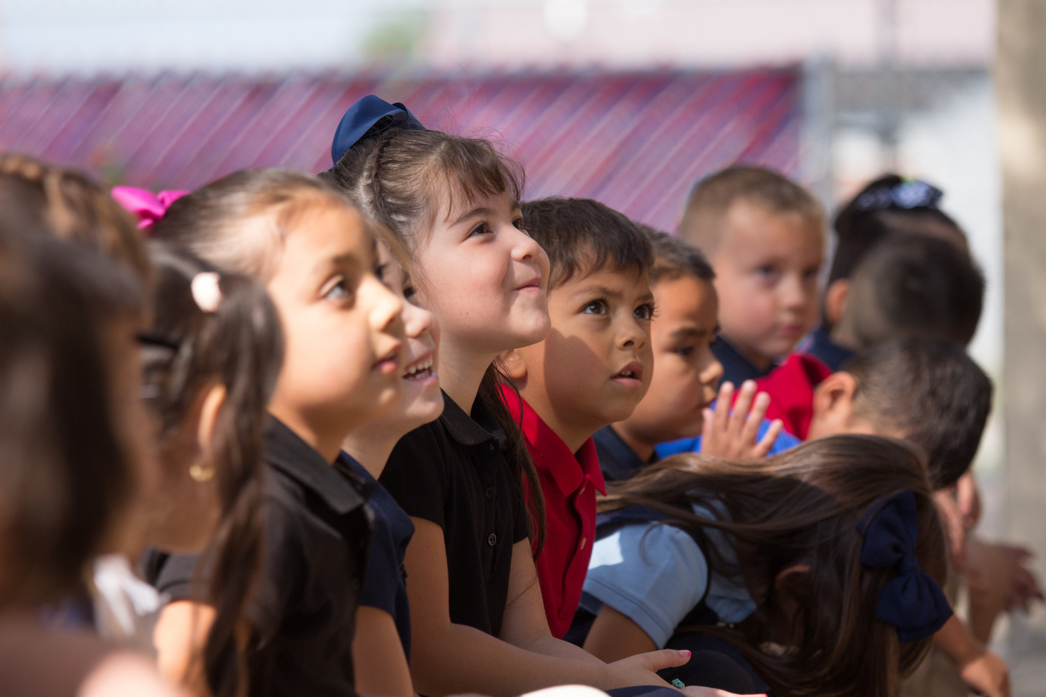 A group of young children with child in center looking up and smiling