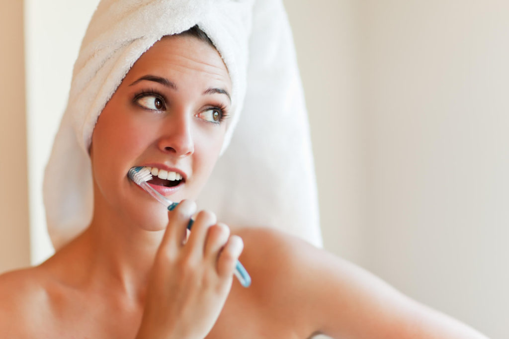 woman brushing her teeth from cosmetic dentist in New Hope