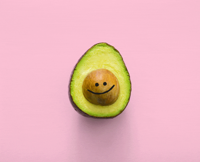 Avocado with wiggly smiley face on pink background