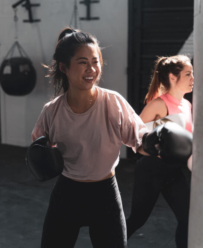 A woman smiling at a boxing class at the gym