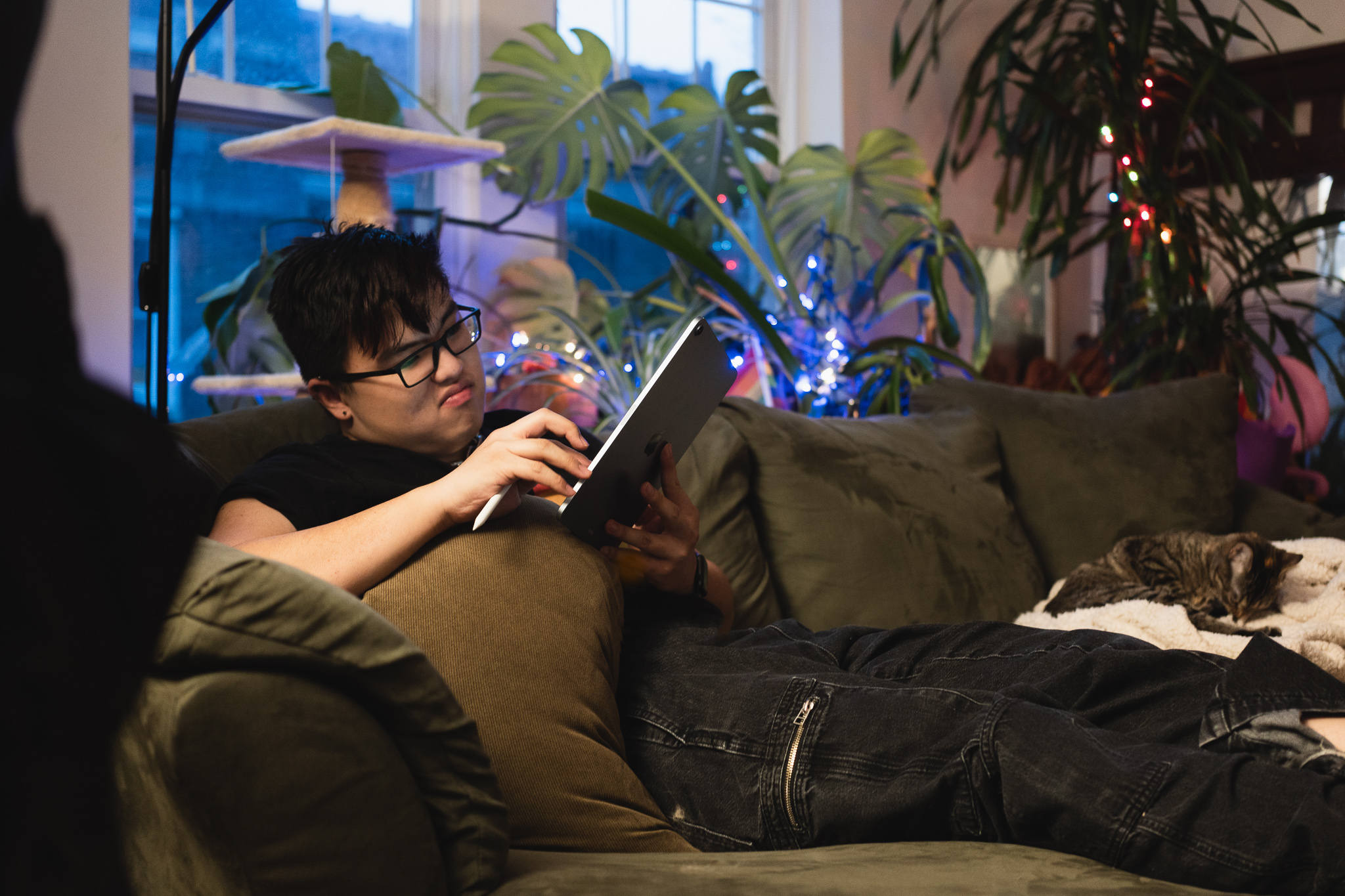 Leo leans back in a couch whilst inspecting a tablet computer.