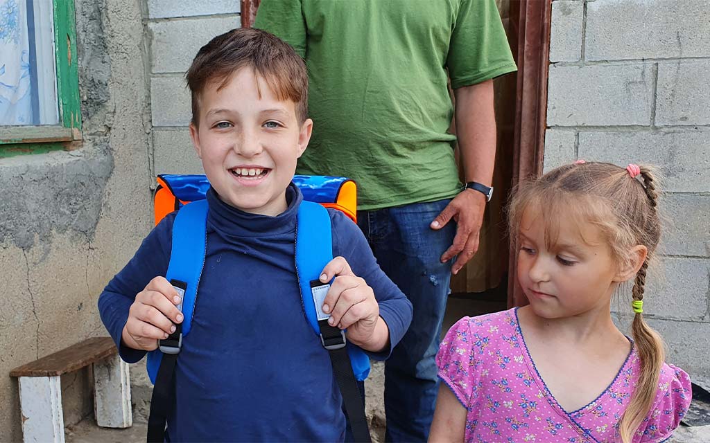 Junge in Moldawien trägt stolz seinen neuen Schulsack aus der Schweiz