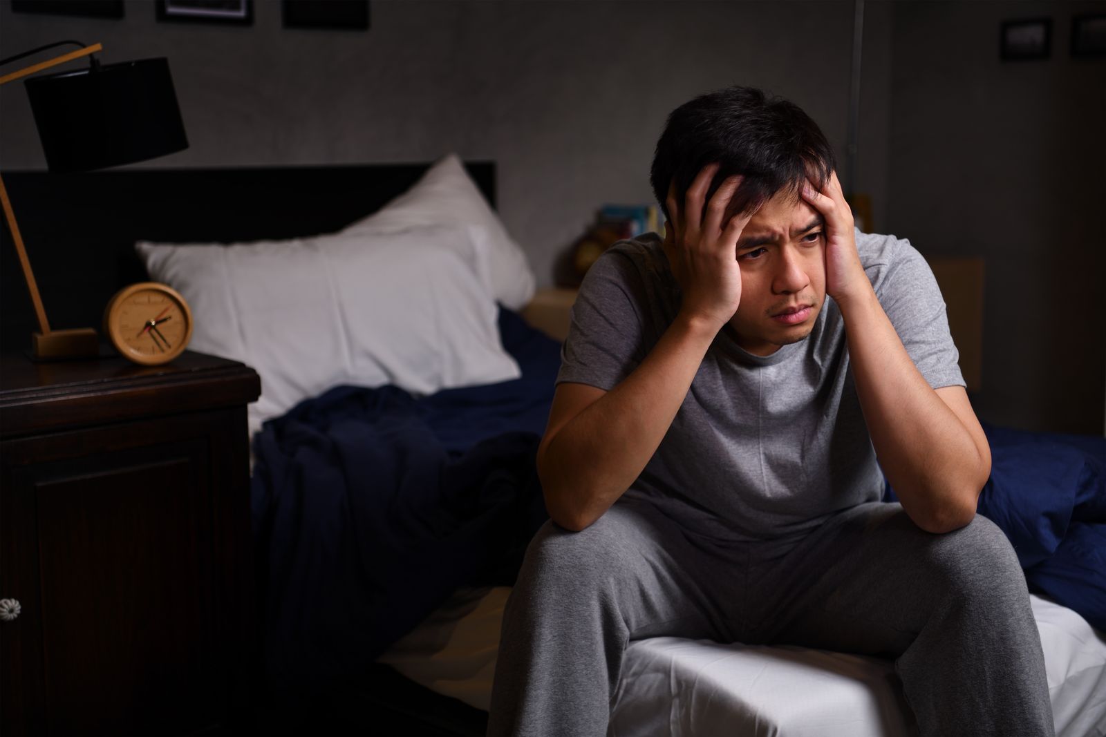 a man holding his head while on a bed is having a severe and high-functioning anxiety