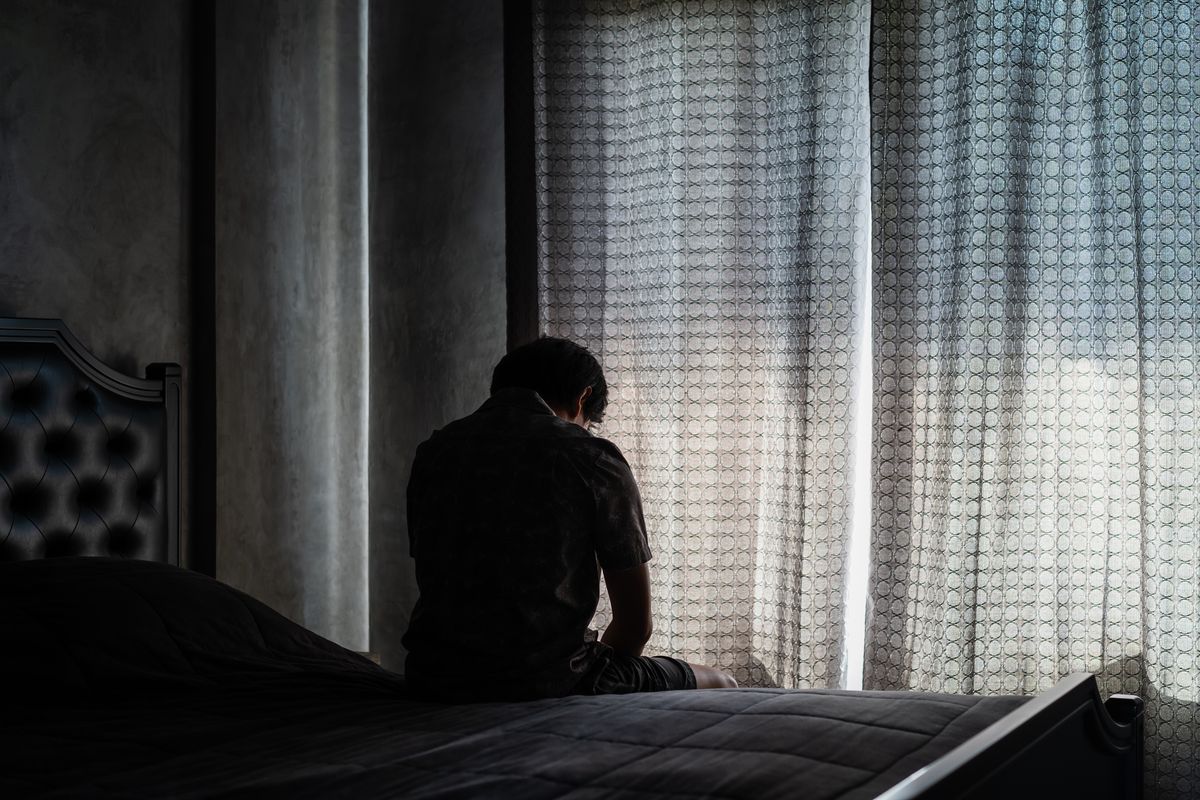 a man who is lonely and depressed is sitting on his bed while high on shatter drug
