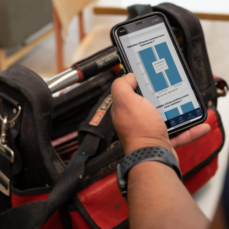 Main qui tient un téléphone avec des statistiques sur l'écran et un caisse à outil en fond