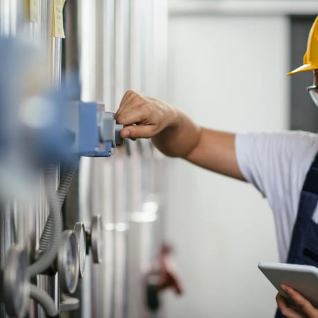 Technicien avec un caque jaune qui répare un tableau électrique