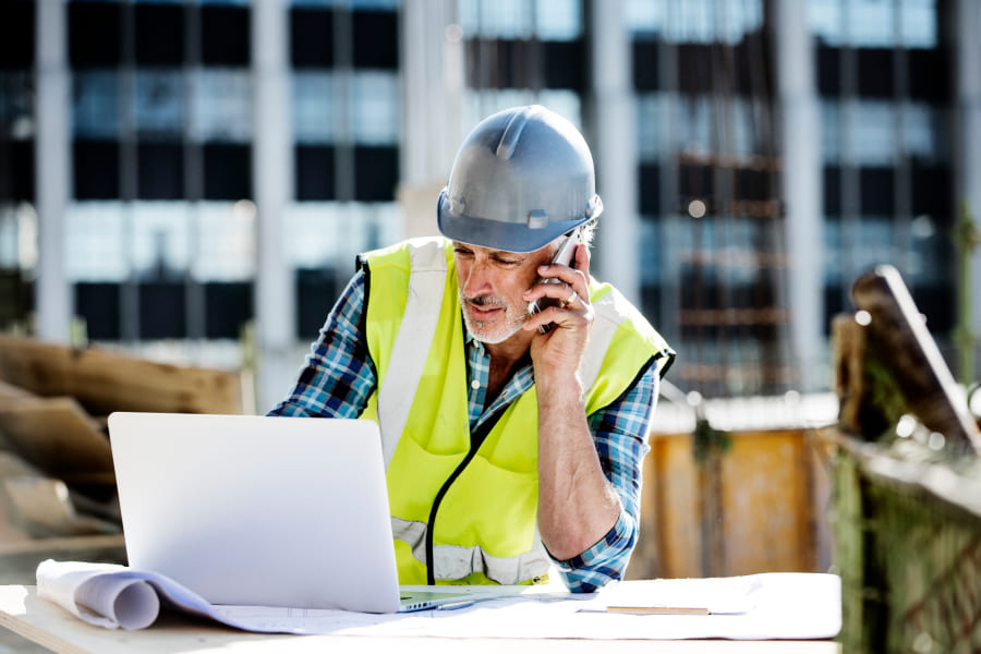 Chef de chantier qui regarde un plan et qui téléphone