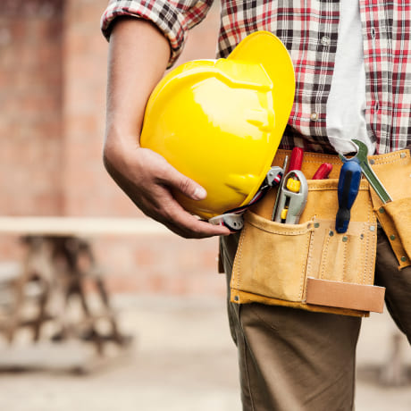 Artisan du bâtiment qui tient un casque de chantier dans sa main