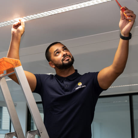 Technicien de maintenance sur une échelle qui répare des leds