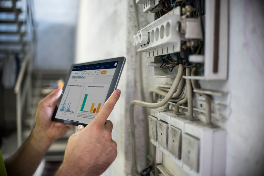Mains de technicien de maintenance qui tient une tablette avec un dashboard statistiques de l'Application Merci Jack