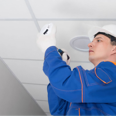 Technicien en système de sécurité incendie installant un détecteur de fumé