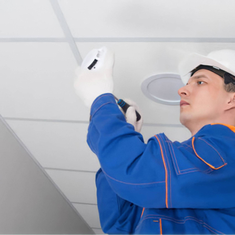 Technicien en système de sécurité incendie installant un détecteur de fumé