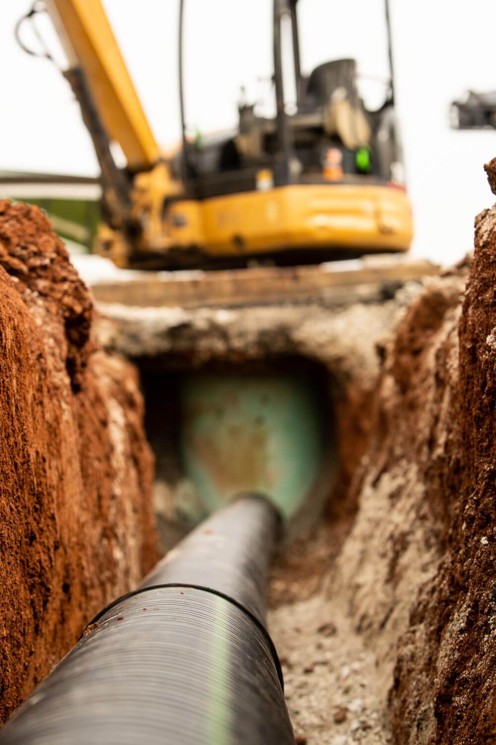 Installing drain pipe for stormwater management system in existing parking lot.