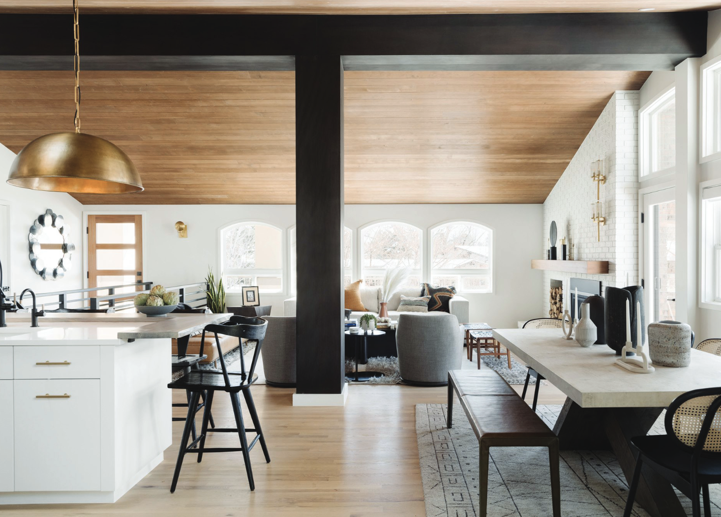 An open plan kitchen/lounge/diner with high, wooden panelled, sloping ceiling and long windows