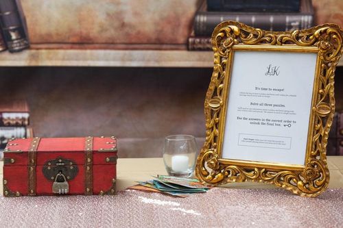 A locked red box sits next to a fancy gold frame with instructions on how to unlock the box