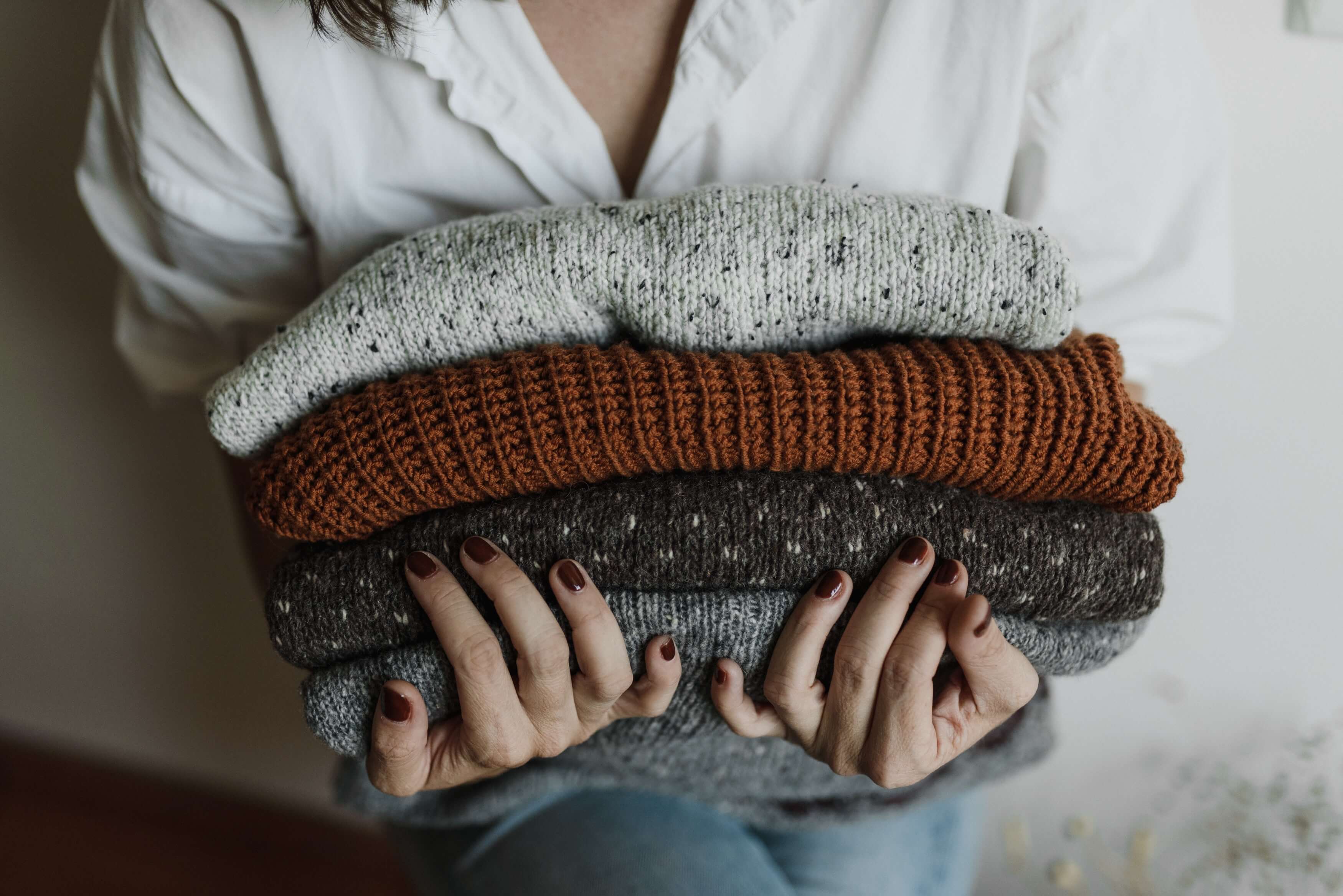 Girl holding a pile of sweaters meant for selling online