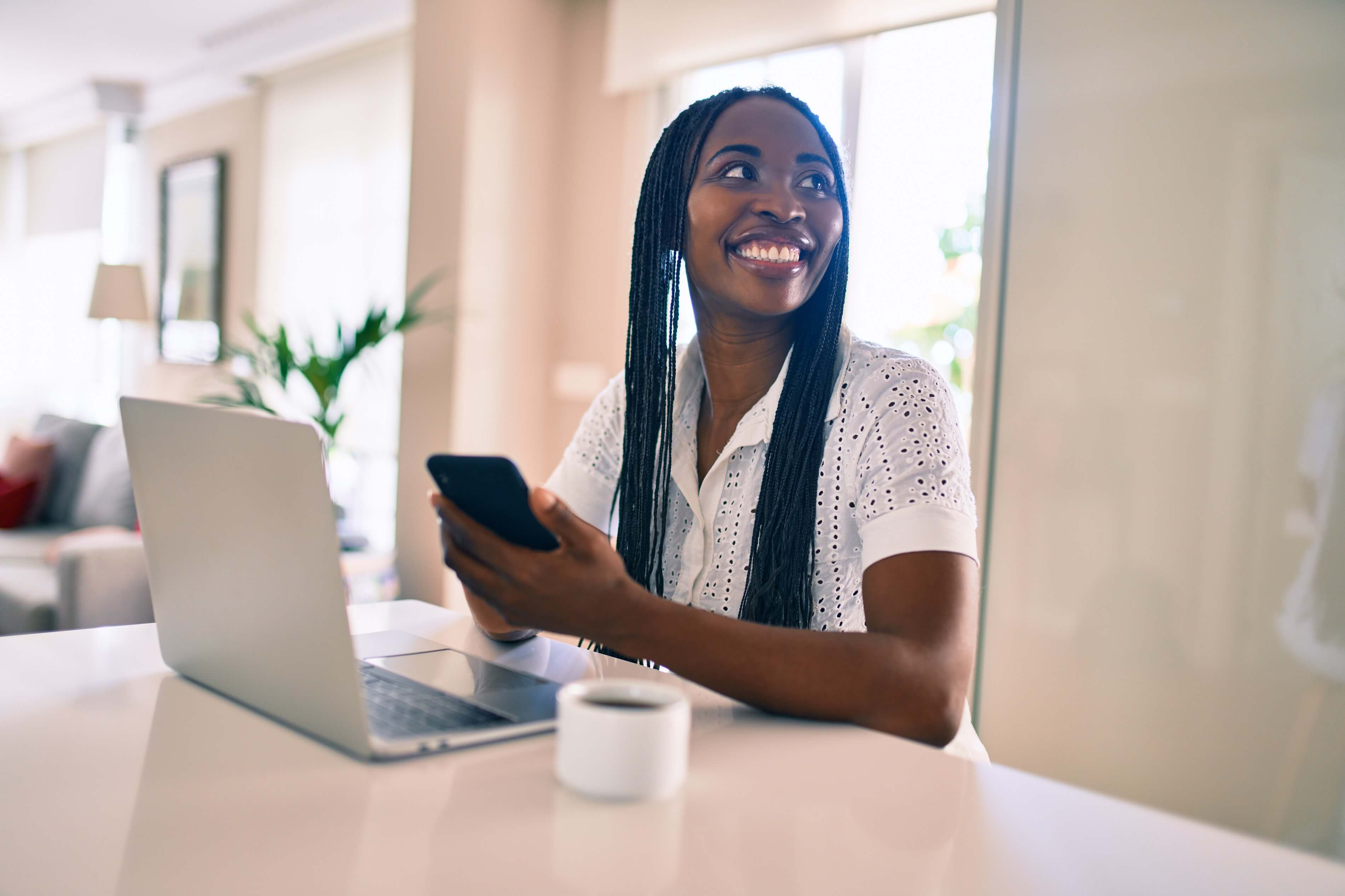 smiling woman working on her laptop and smartphone