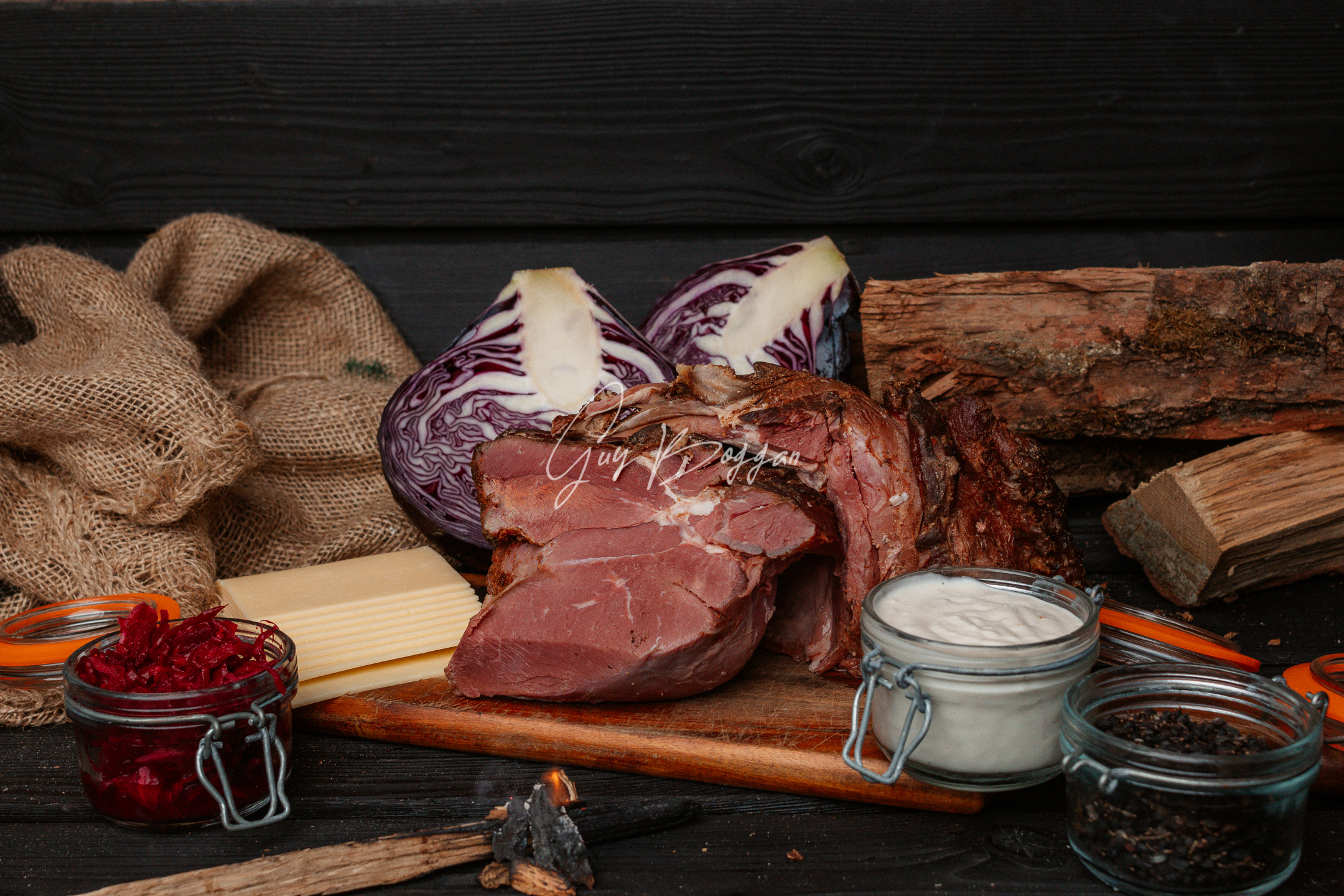 A selection of ingredients on display including a piece of cut raw beef, some cheese slices and a cut red cabbage