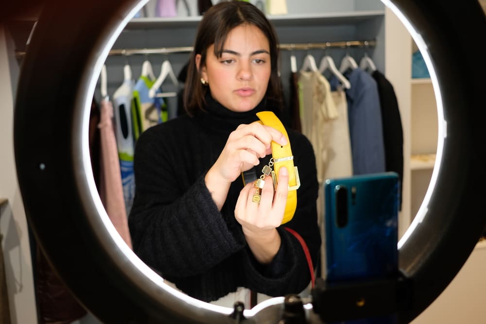Une animatrice de Live Shopping présente une ceinture jaune éclairée par une lampe circulaire