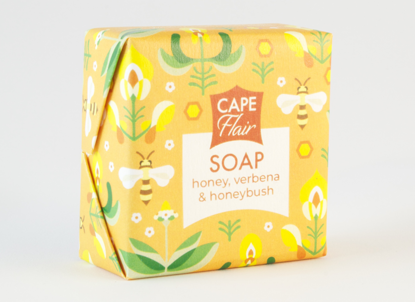 A honey and honeybush soap bar wrapped in a beautiful orange wrapper with bees and flowers on. 