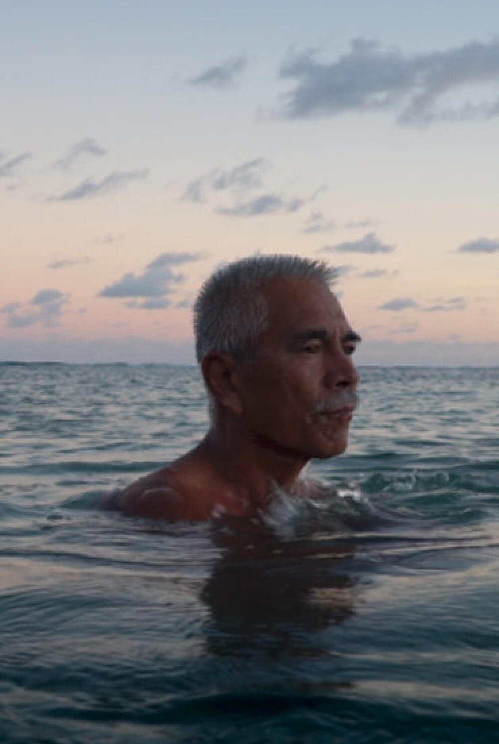 Anote Tong, former president of Kiribati, bathes in the sea during golden hour.