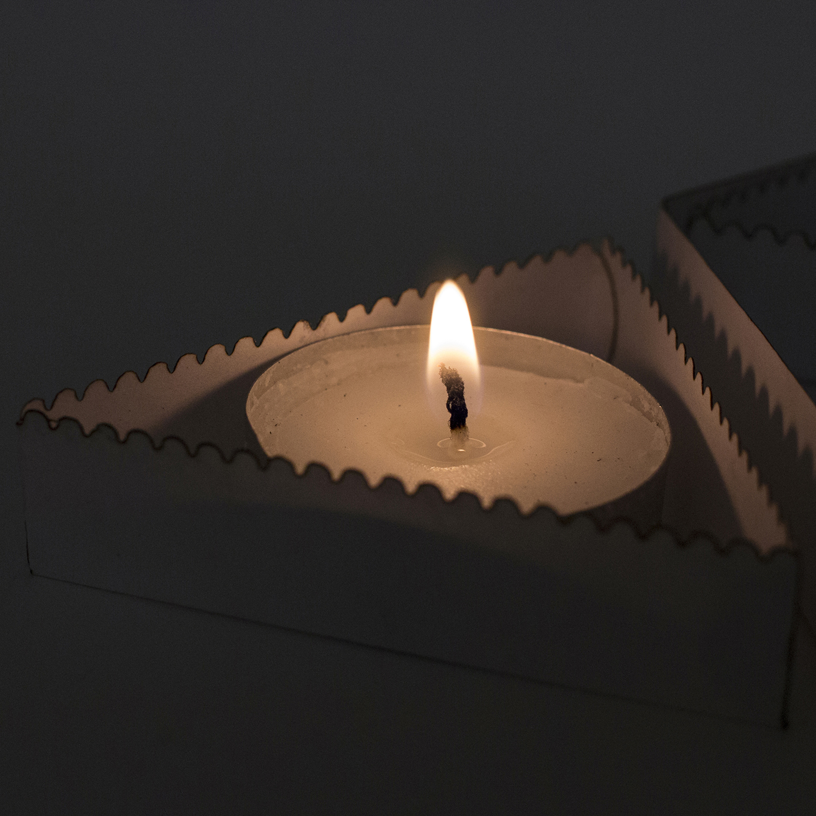 Lit candle in interior packaging, lights off.