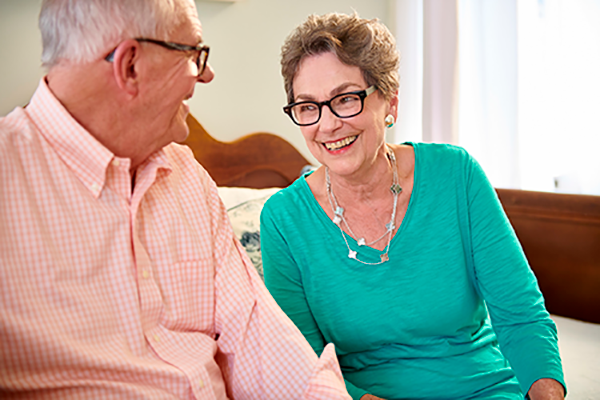 Older couple, man and woman, sitting on a couch, talking.
