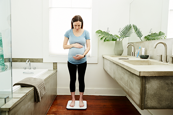 Pregnant woman standing on scale.