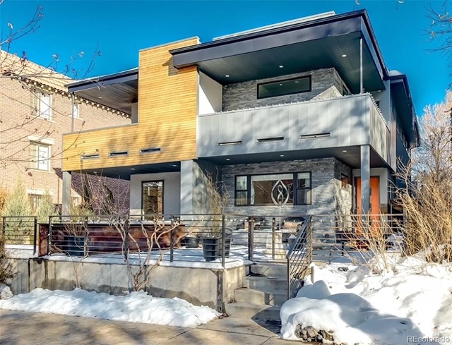 A two story modern house on a sunny day with snow on the ground