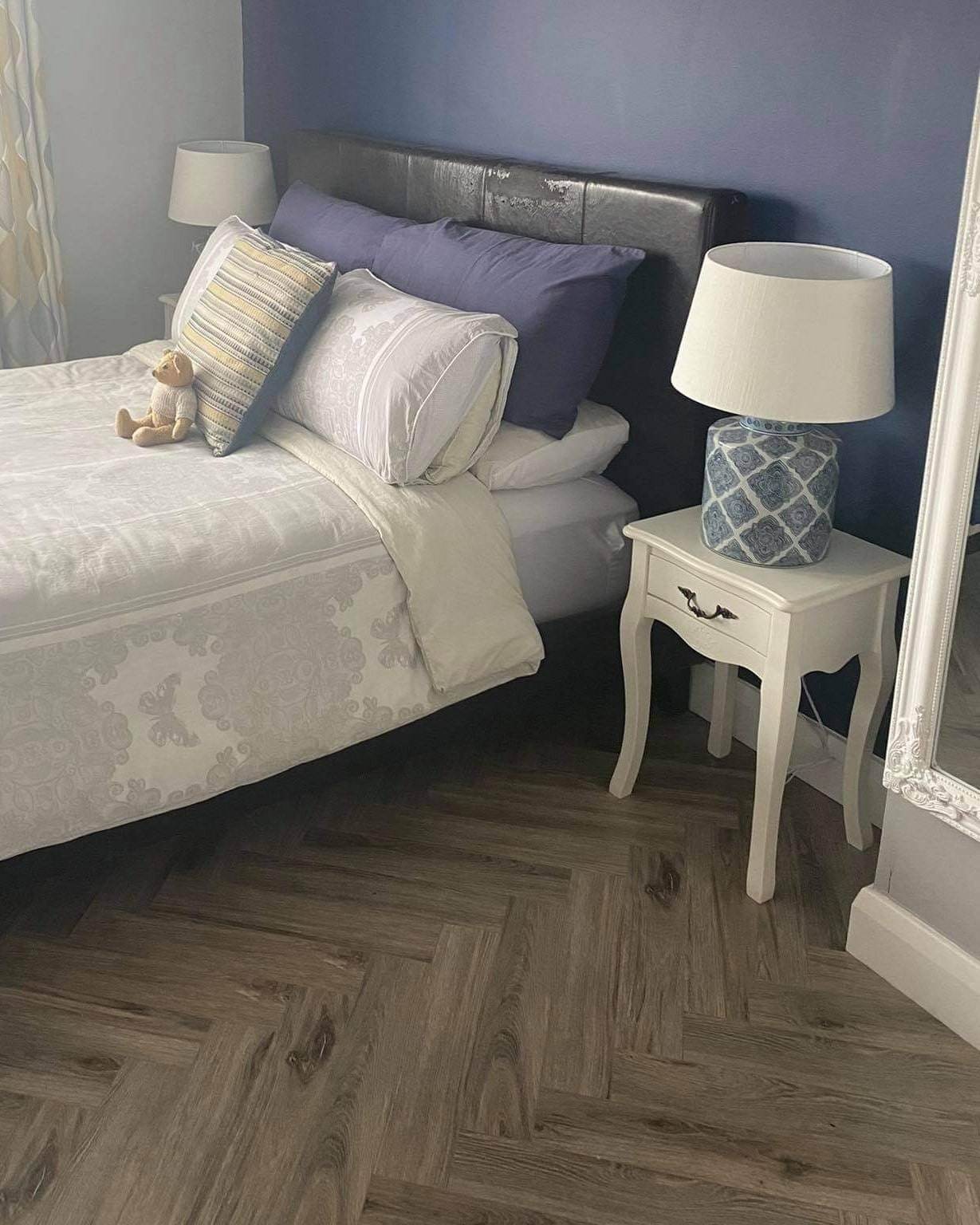 Parquet floor in bedroom and bed with side table and lamp