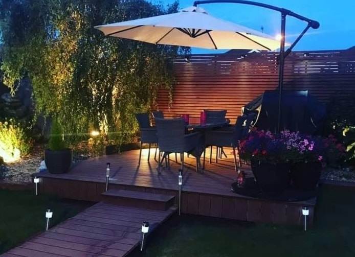 Image of garden with decking, fencing, umbrella and nice lights