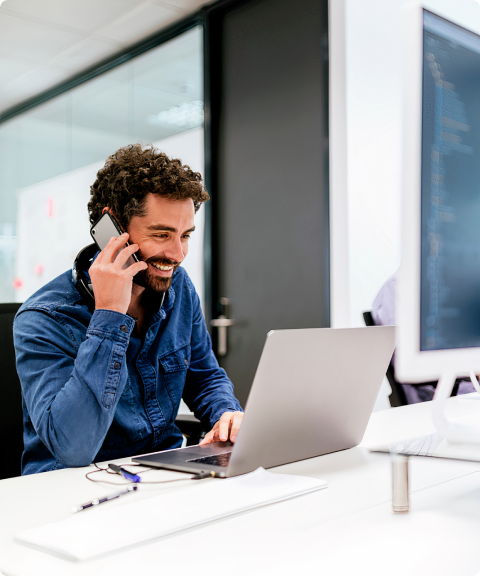A man smiling while talking on the phone in an office