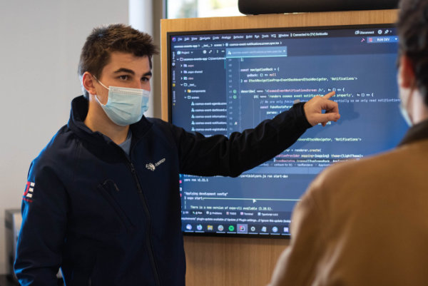 Students are discussing programming in front of a screen display