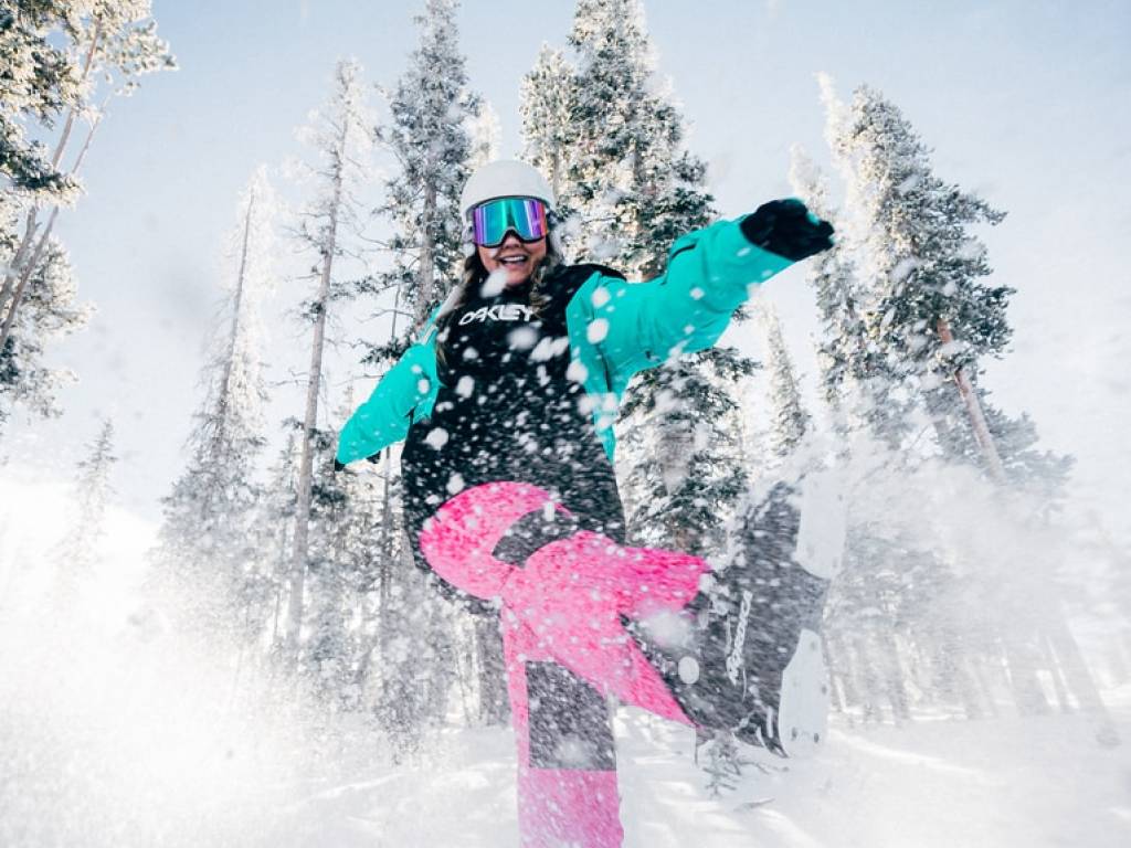 A person dressed in ski gear kicking snow.