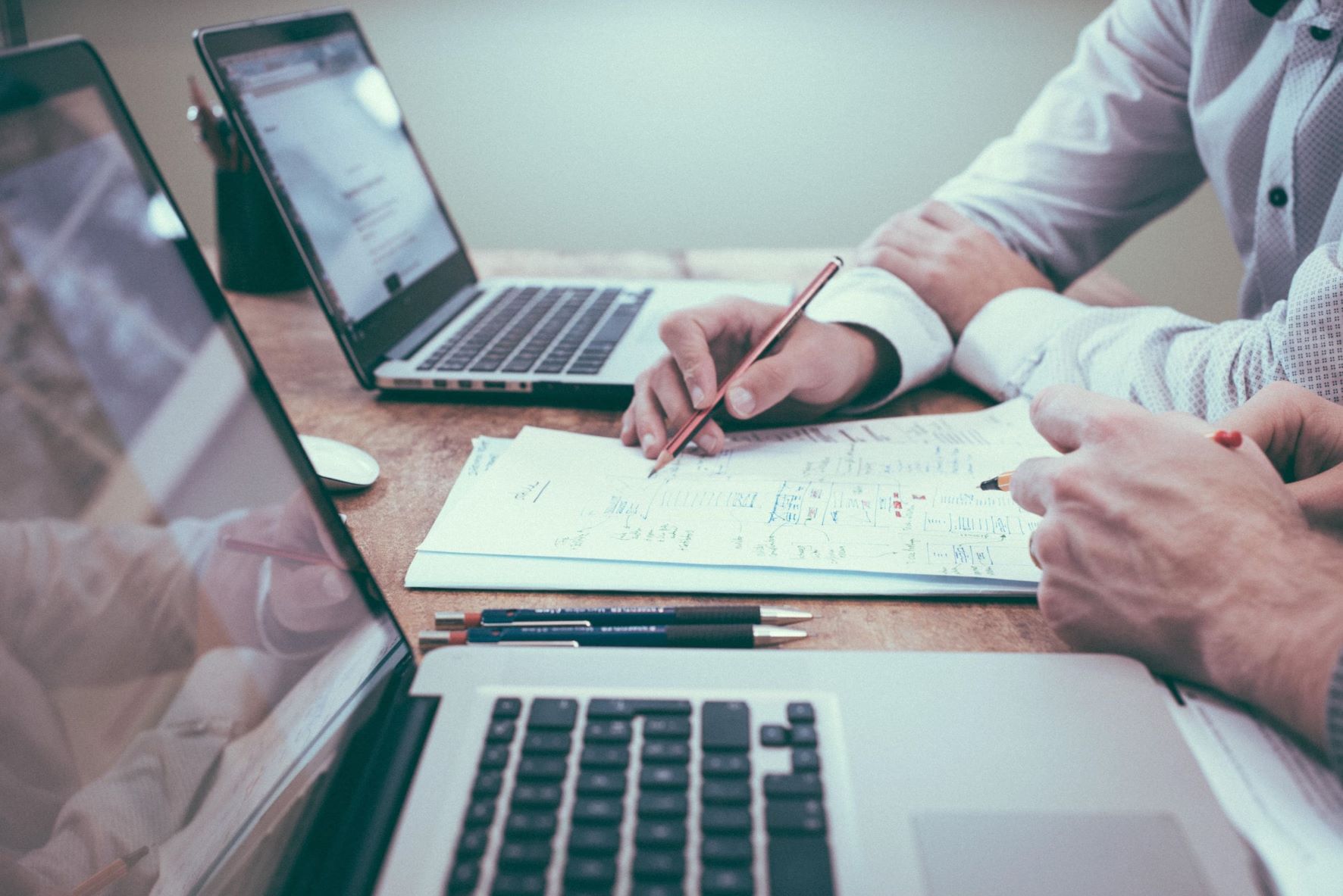 Zwei Personen arbeiten an Dokument und Laptops