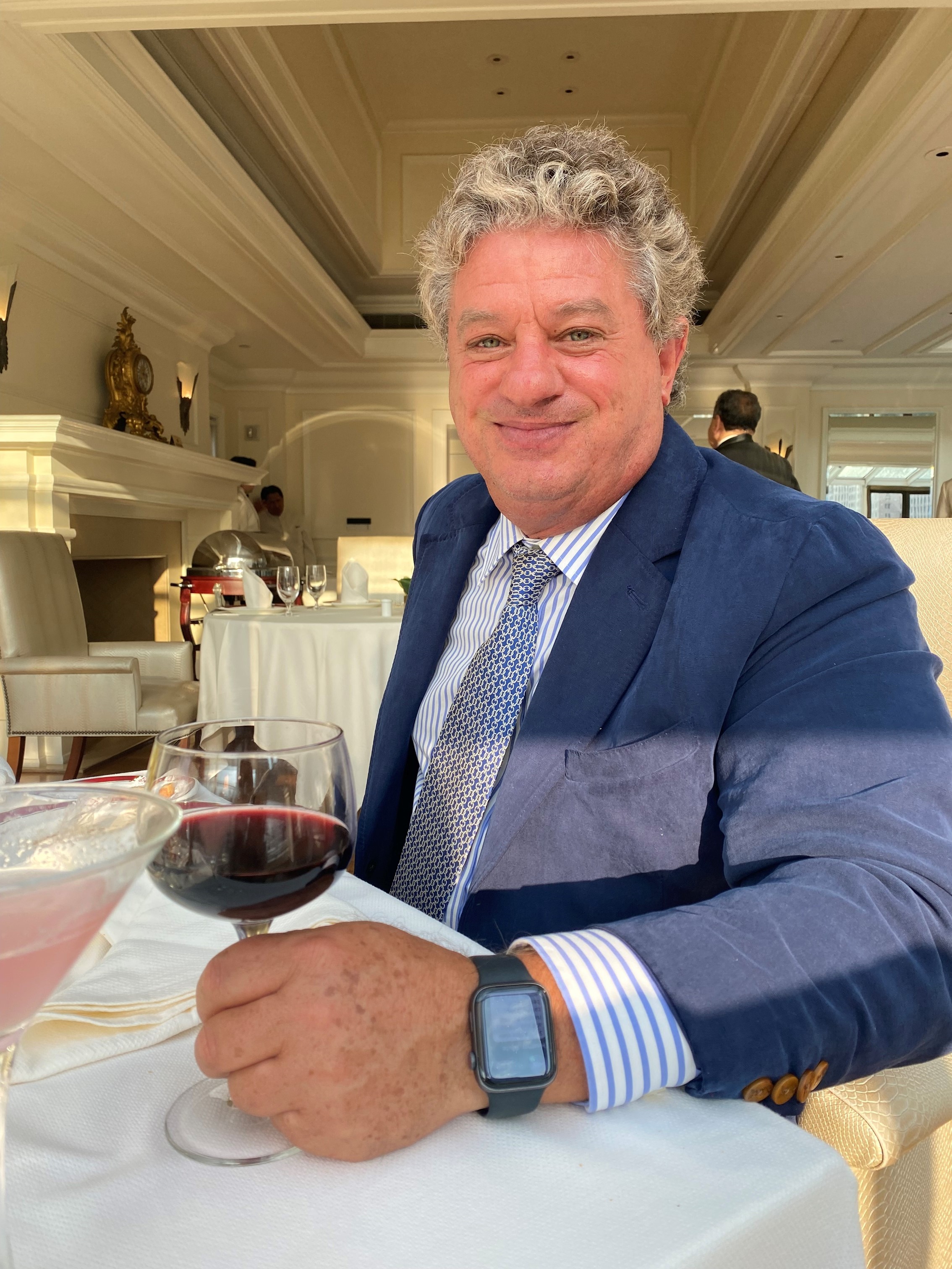 Andrew smiling in a suit holding a wine glass