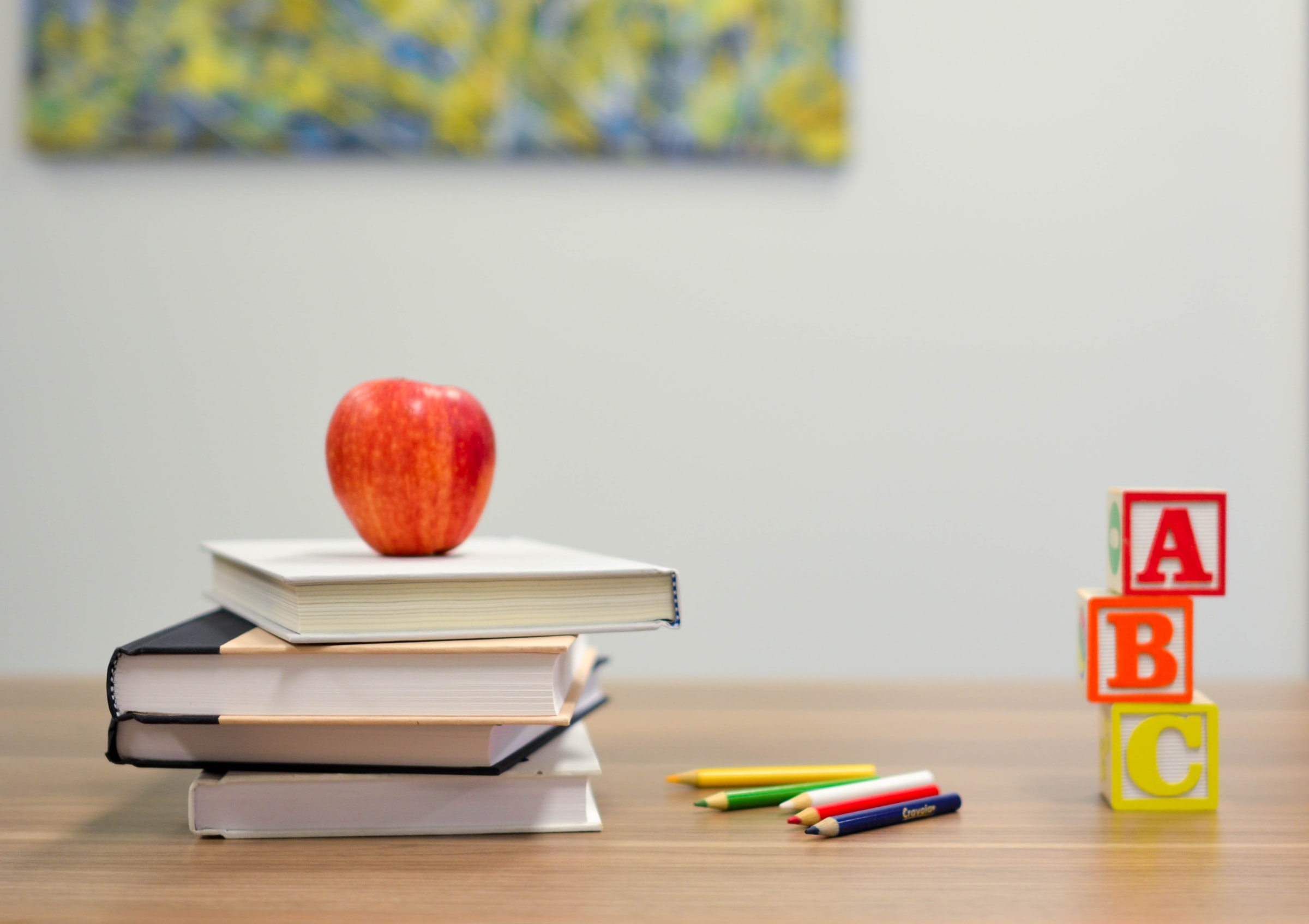 a desk with books, colored pencils, and an apple on it