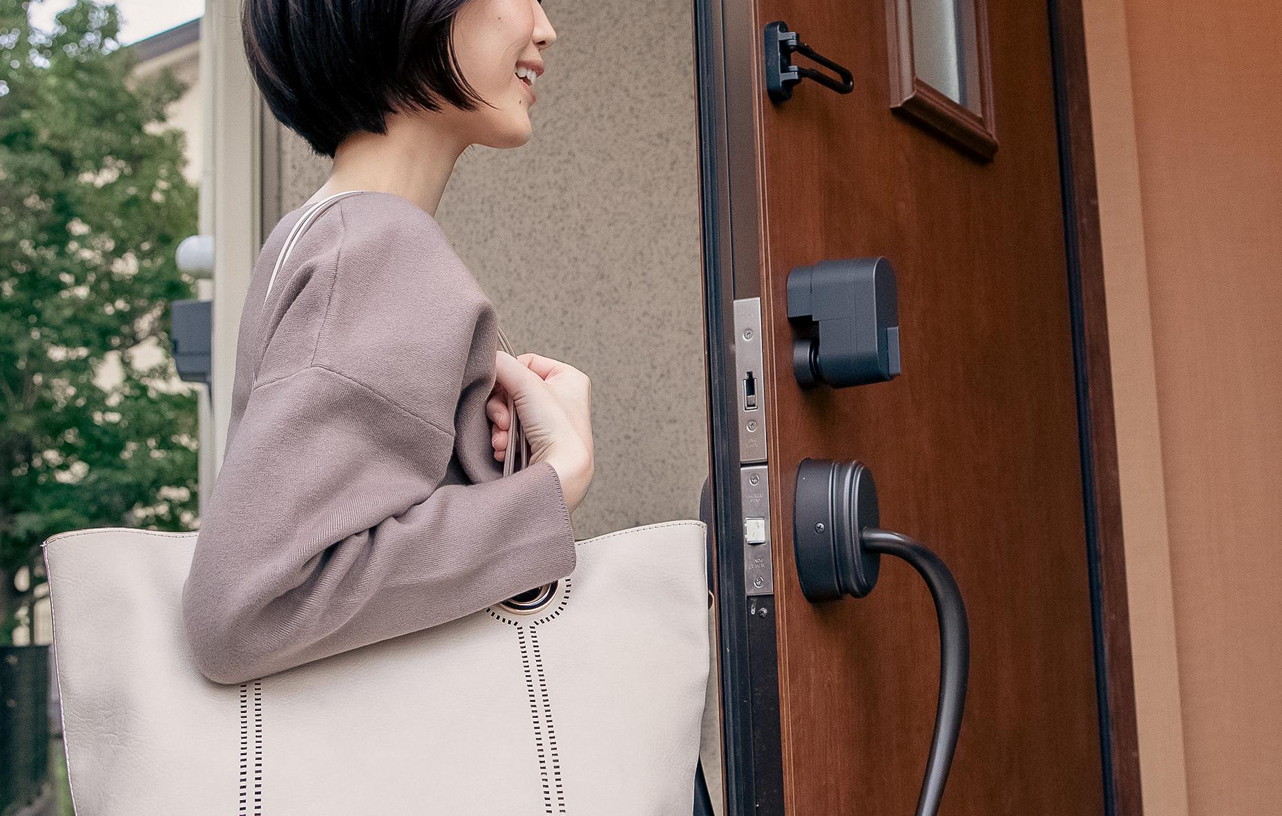 A woman opening a wooden door with a smile while the bitlock MINI is attached to it on the inside