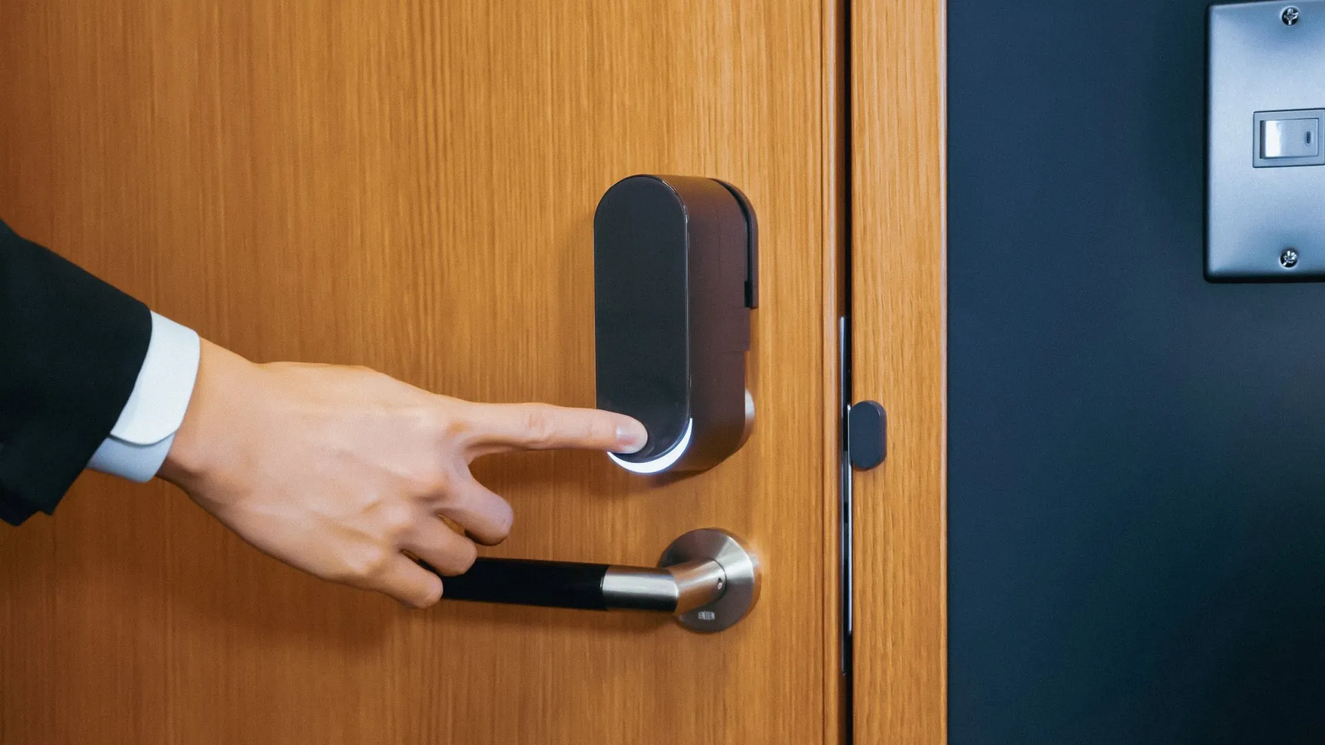 A hand interacting with the bitlock PRO while it is attached to a door