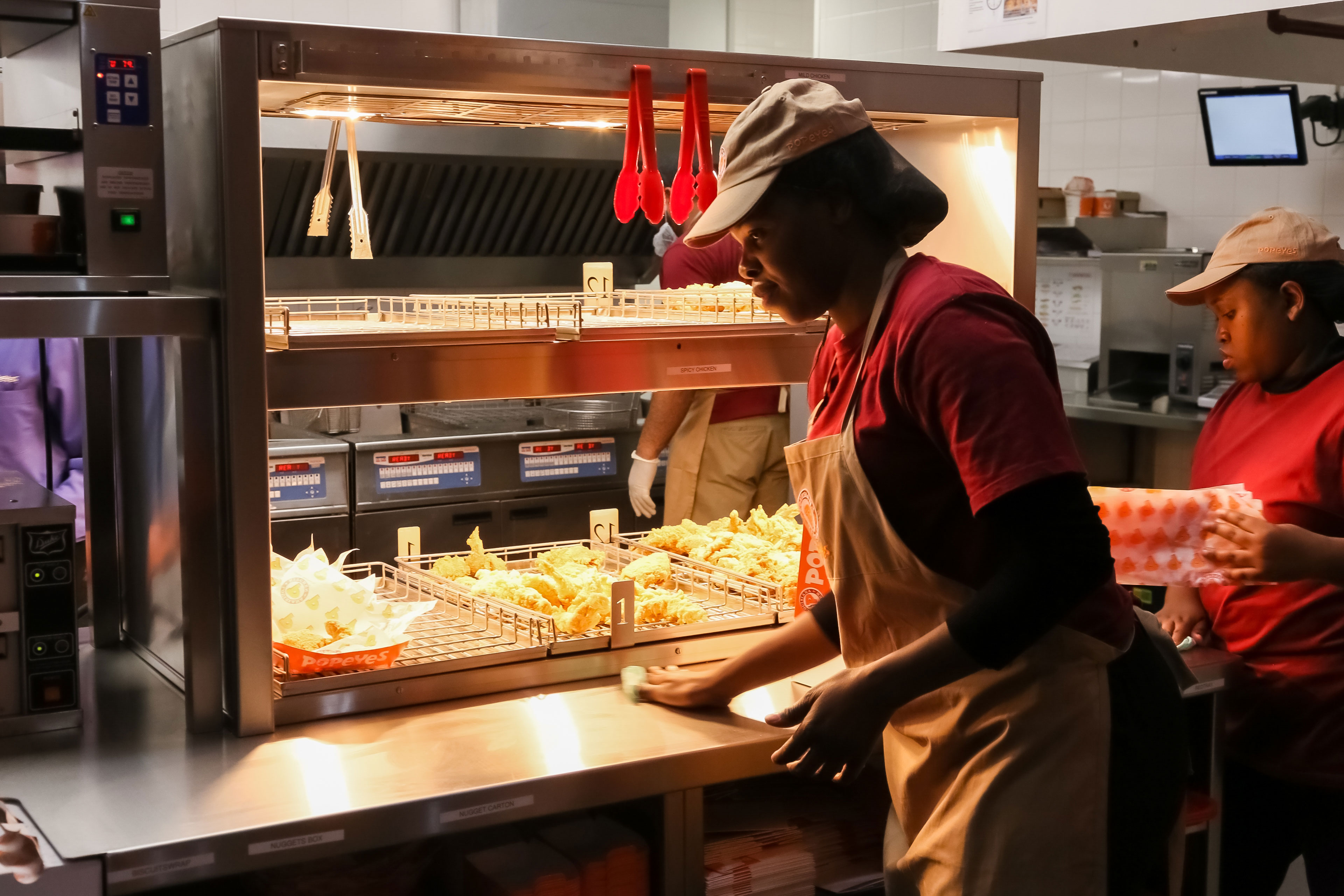 Foto de uma mulher produzindo itens em uma cozinha de uma grande rede de fast food