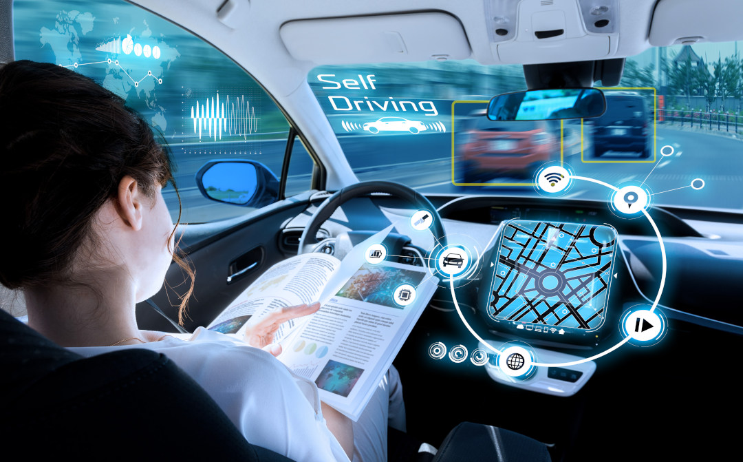 A person reads a magazine inside a self-driving car, surrounded by digital displays showing navigation, car status, and traffic data, illustrating autonomous driving technology.