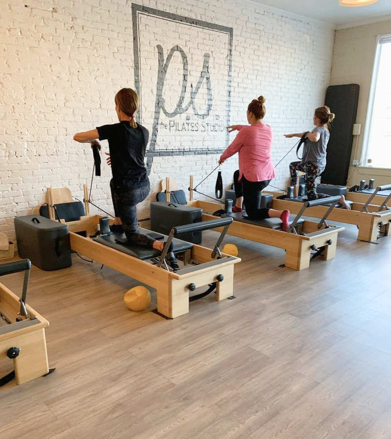 A group session in a pilates studio with their backs to the camera